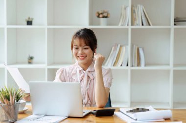 Neşeli Çalışan, başarısını kutlarken aynı zamanda ofisteki laptopta iyi haberler okuyor..