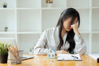 Stresli bir iş kadını masada otururken dizüstü bilgisayarda çalışır ve elini şakaklarına koyar, migren krizi geçirir...