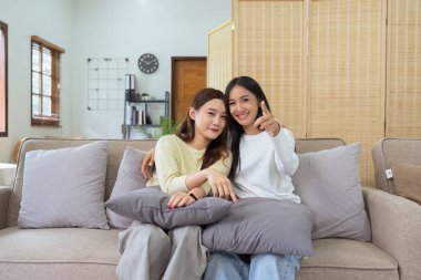 Asyalı lezbiyen kadın çift evde birlikte TV izlemekten ve televizyonda mutlu bir film izlemekten hoşlanıyor. Homoseksüel-LGBTQ kavramı..