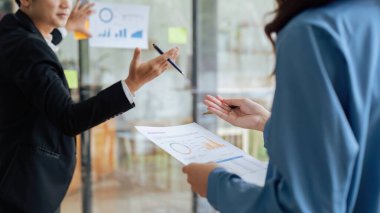 Belgeleri grafikle gösteren iş adamları. Şirketlerin gelirlerindeki istikrarlı artışı sunar.