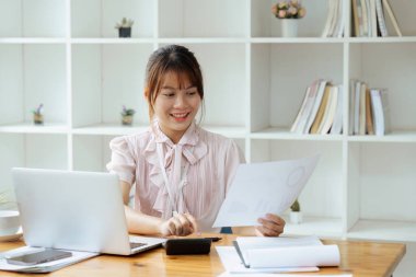 Ofis içinde evrak işi yapan bir çalışan, kadın finansör sözleşmeleri ve grafiklerle ilgili raporları düşünüyor, başarılı kadın iş yerinde dizüstü bilgisayar kullanıyor..