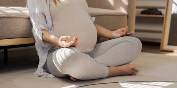 Healthy Pregnancy Yoga and Fitness. Young pregnant yoga woman and meditation in living room.