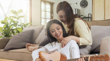 LGBTQIA lezbiyen çift gitar çalıyor ve evde romantik duygularla şarkı söylüyorlar..
