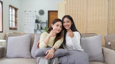 Asyalı lezbiyen kadın çift evde birlikte TV izlemekten ve televizyonda mutlu bir film izlemekten hoşlanıyor. Homoseksüel-LGBTQ kavramı..