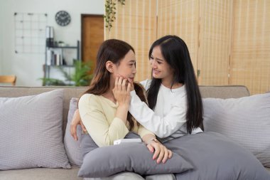 Livingroom 'da birlikte gülen LGBTQIA lezbiyen çifti. Asyalı LGBTQIA lezbiyen çift kanepede otururken birlikte mutlu bir şekilde güldüler. Homoseksüel-LGBTQ kavramı.