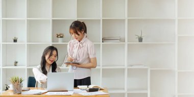 Ofiste birlikte çalışan iş adamları dizüstü bilgisayara bakarak ve ofiste yeni projeleri tartışarak yeni projeler planlıyorlar...