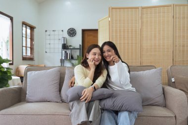 Asyalı lezbiyen kadın çift evde birlikte TV izlemekten ve televizyonda mutlu bir film izlemekten hoşlanıyor. Homoseksüel-LGBTQ kavramı..