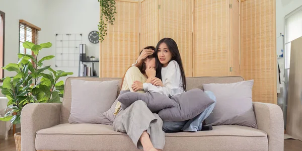 Asian lesbian woman couple enjoy watch TV together in house and feel scared watch movie on television. Homosexual-LGBTQ concept..
