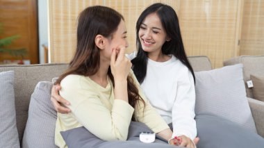 Livingroom 'da birlikte gülen LGBTQIA lezbiyen çifti. Asyalı LGBTQIA lezbiyen çift kanepede otururken birlikte mutlu bir şekilde güldüler. Homoseksüel-LGBTQ kavramı..