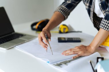 Mühendis dairesel aletlerle bir taslak çizmeyi planlıyor. Masadaki mimari ekipman ve mimari planlarla birlikte..