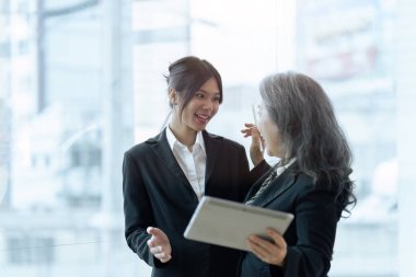 İki mutlu iş arkadaşı tablet üzerinde mali raporları tartışıyor, proje üzerinde birlikte çalışıyorlar..