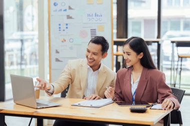 İş adamı yöneticisi, Asyalı meslektaşının finansal projesini dizüstü bilgisayarında açıklıyor ve yönetiyor..