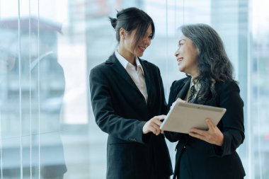 İki mutlu iş arkadaşı tablet üzerinde mali raporları tartışıyor, proje üzerinde birlikte çalışıyorlar..