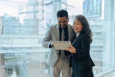 Tablet hakkındaki raporları tartışan iki mutlu iş arkadaşı, proje üzerinde birlikte çalışıyorlar..