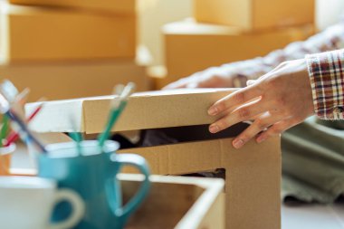 Genç adam yeni eve taşınmak için karton kutuyu açık tutuyor..