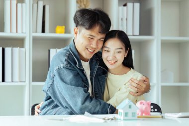 Genç çift ev kredisi sözleşmesini başarıyla tamamlayarak ev satın almak için finansal plan yapıyor..