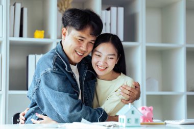 Genç çift ev kredisi sözleşmesini başarıyla tamamlayarak ev satın almak için finansal plan yapıyor..