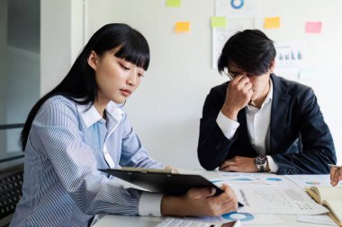 Ofisteki masada otururken belgeleri analiz eden ekip. Ofisteki kadın yöneticiler bazı evrak işlerini tartışıyorlar..