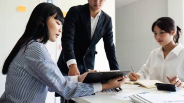 Ofisteki masada otururken belgeleri analiz eden ekip. Ofisteki kadın yöneticiler bazı evrak işlerini tartışıyorlar..