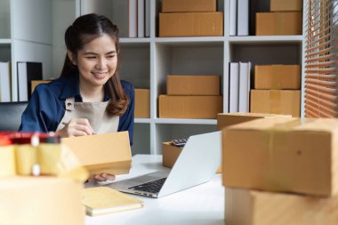 Genç bayan çevrimiçi işyeri sahibi paketin teslimatı için bir paket hazırlıyor..
