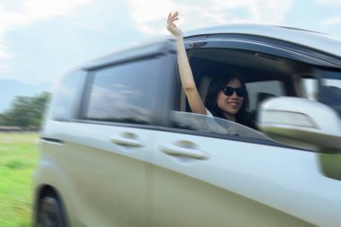 Kadın arabayı sürüyor ve rüzgarı hissetmek için ellerini arabanın dışına sokuyor. seyahat kavramı.