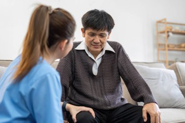 fizyoterapist ya da bakıcı yaşlı bir adamın dizlerini esnetmesine yardım ediyor..