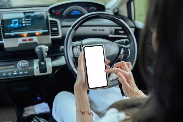Woman driver using mobile phone screen blank mockup inside a car in sunny day.