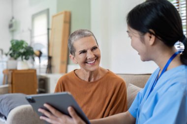 Asyalı hemşire yaşlılara sağlık kontrolü raporu veriyor ve tavsiye veriyor. Ev bakımı ve sağlık bakımı kavramı.