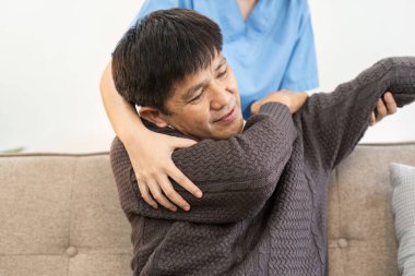 Asyalı kadın doktor yaşlı hastaya evde egzersiz yapmasını tavsiye ediyor..