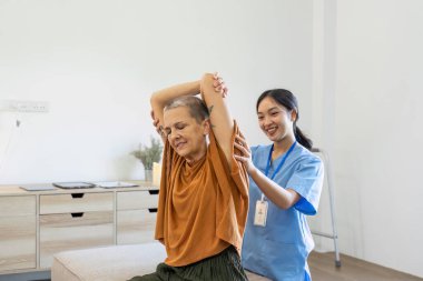 Asian female doctor advice elderly patient to physiotherapist to exercise at home. clipart