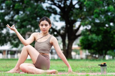 Spor giysiler giyen Asyalı bir kadın doğada yoga yapıyor..