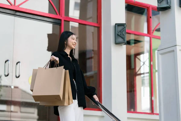 Young asian woman in shopping. Fashion woman in black with shopping bag walking out store after shopping. Black friday.