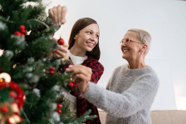 Anne ve kız, Noel ağacını Noel 'e hazırlanmak için süslüyor..