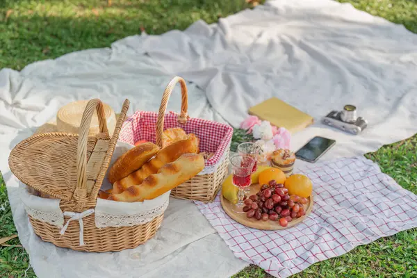 Picnic basket with fruit and bakery on a blanket in the park. Summer picnic with fresh fruits and croissants in the garden.