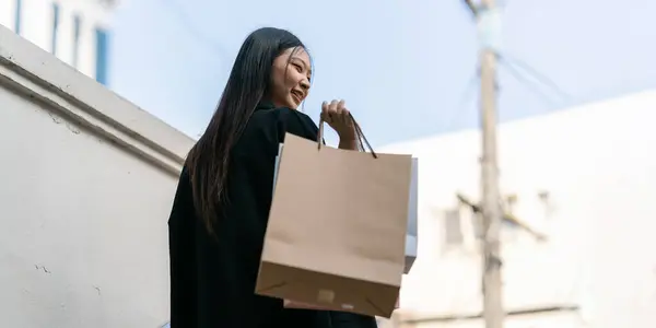 Young asian woman in shopping. Fashion woman in black with shopping bag walking around the city after shopping. Black friday.