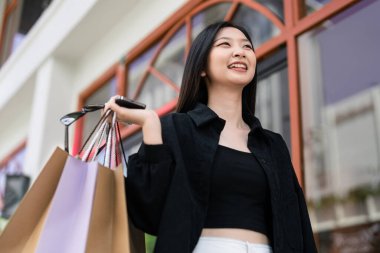 Alışveriş yapan Asyalı genç bir kadın. Alışveriş yaptıktan sonra şehirde dolaşan siyah elbiseli bir kadın. Kara Cuma.