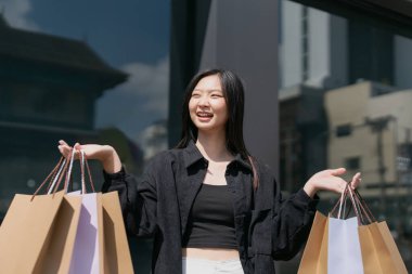 Alışveriş yapan Asyalı genç bir kadın. Alışveriş yaptıktan sonra şehirde dolaşan siyah elbiseli bir kadın. Kara Cuma.