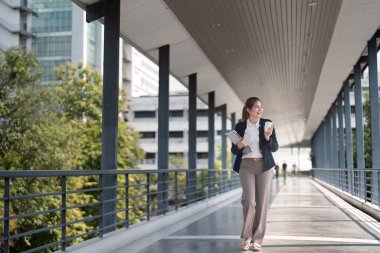 Asyalı genç iş kadını şehirde işe giderken gökyüzünde yürümekten mutlu..