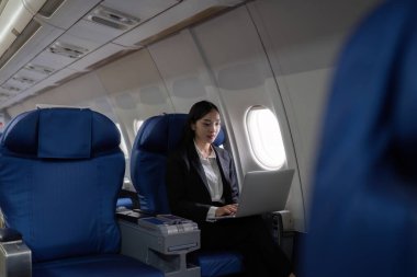 Uçakta dizüstü bilgisayarla çalışan Asyalı güzel bir iş kadını. çalışma, seyahat, iş konsepti.