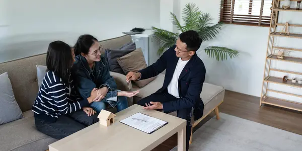 stock image Happy real state agent giving new house key to a young lesbian LGBTIQA couple.