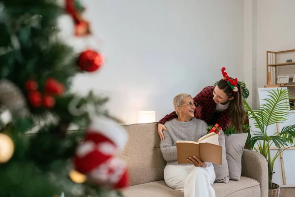 Daughter Surprise gift mother for Christmas while mother was reading book on couch.