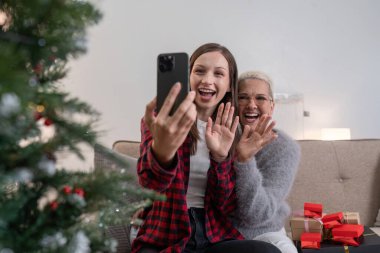 Noel 'i kutlayın, yeni yıl sezonu, elinde akıllı telefon selfie' si olan anne ve kız sosyal mesafede görüntülü arama yaparak fotoğraf çekin..