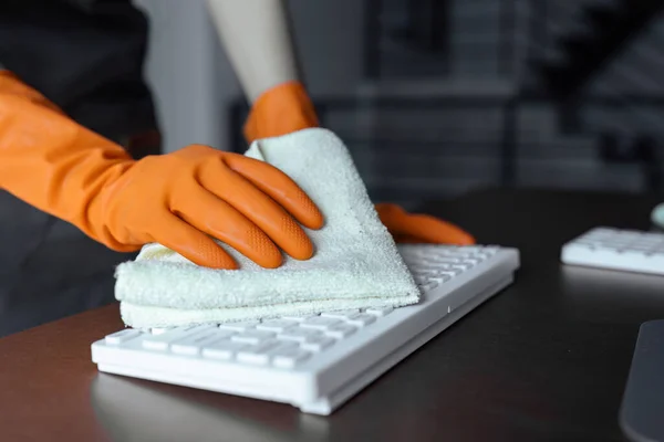 Woman maid cleaning and wiping the keyboard with microfiber cloth in office. cleaning concept.