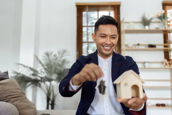 Young man agent real estate agent holding house mockup with keys. Real estate concept..