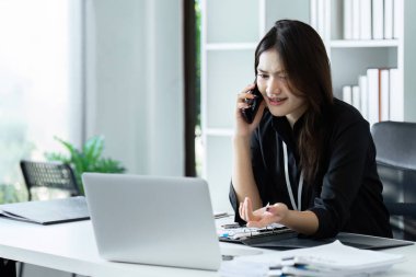 İş kadını telefonda ve ofisteki bilgisayarı kullanıyor. İş kadını profesyonel cep telefonuyla konuşuyor.