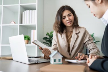 Emlakçı yeni ev alıcılarıyla konuşur, iyi faiz oranları teklif eder ve mortgage finansmanında müşterileri hesaplar..