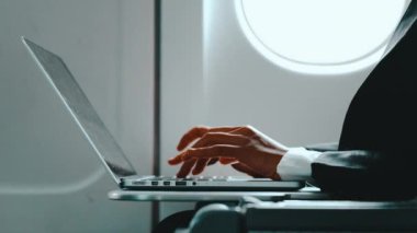 İşadamı elleri dizüstü bilgisayar klavyesinde uçak işinde seyahat ederken 4K, iş kadını tablet bilgisayar üzerinde çalışıyor.