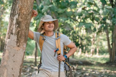 Genç adam ormanda tek başına seyahat ediyor. Tatil gezisi sırasında doğa ormanında yürüyen çekici erkek gezgin..