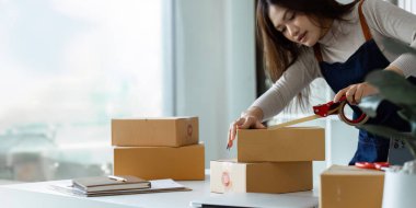 Genç girişimci bir kutuyu bantla mühürlüyor. Nakliyeye, paketlemeye, çevrimiçi satışa, e-ticaret konseptine hazırlık.