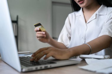 Genç bir kadın internette kredi kartıyla bir şeyler satın alıyor..